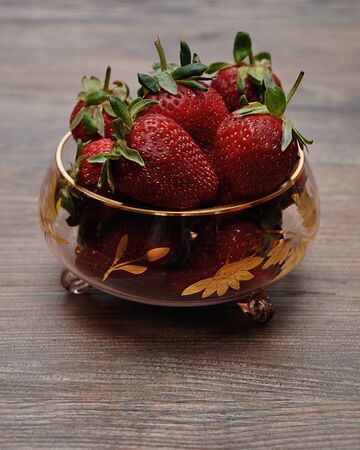 A bowl of strawberries on a wooden backgroundの写真素材