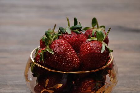 A bowl of strawberries on a wooden backgroundの写真素材