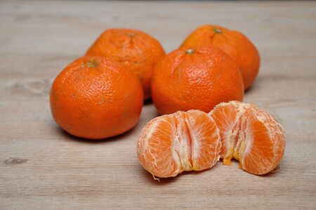 Mandarins on a table with a peeled one split in two halvesの写真素材