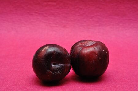 Two ripe plums on a pink backgroundの写真素材