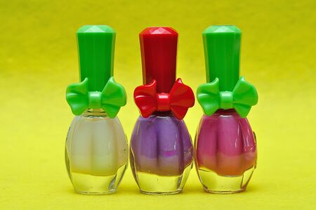 A row of different color nail polish on a yellow backgroundの写真素材