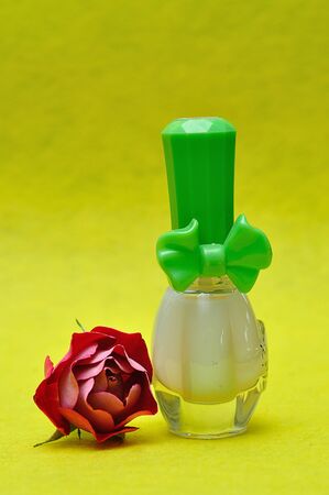 A bottle of white nail polish with a red roseの写真素材