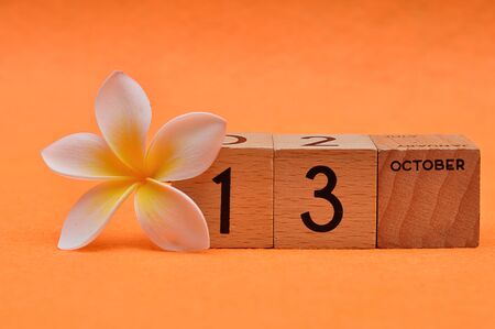 13 October on wooden blocks with a Frangipani flower on an orange backgroundの写真素材