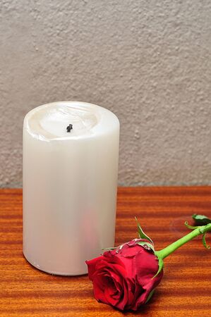 A white candle with a red roseの写真素材