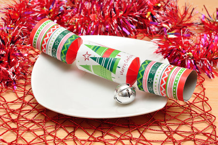 Christmas table decorated with a plate, tinsel, bell and a christmas crackerの写真素材