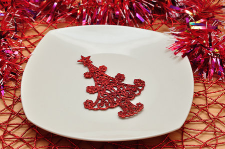 Christmas table decorated with a plate, tinsel, and a christmas treeの写真素材