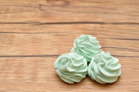 Three green meringues on a wooden backgroundの写真素材