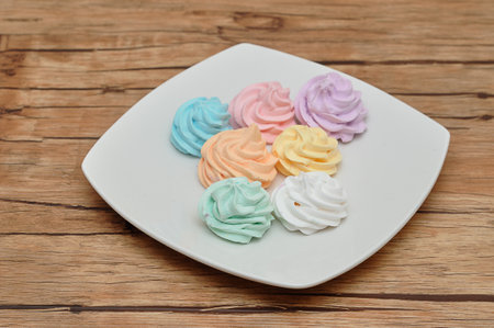A plate with pastel colored meringuesの写真素材