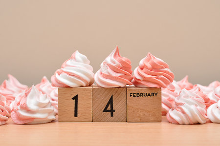 14 February on wooden blocks displayed with pink and white meringuesの写真素材