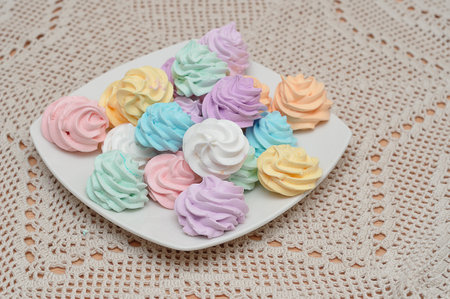 A plate with pastel colored meringuesの写真素材