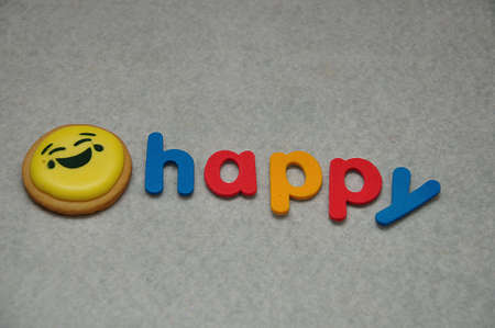 A smiley emoji biscuit with the word happy on a white backgroundの写真素材