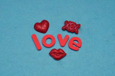 A candy shape lips , red heart and XOX with the word love isolated on a blue backgroundの写真素材