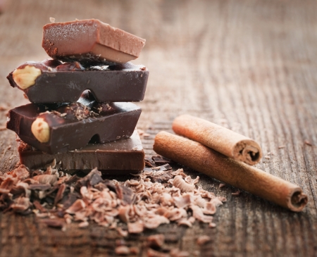 Chocolate pieces  with cinnamon stick on wooden background の写真素材