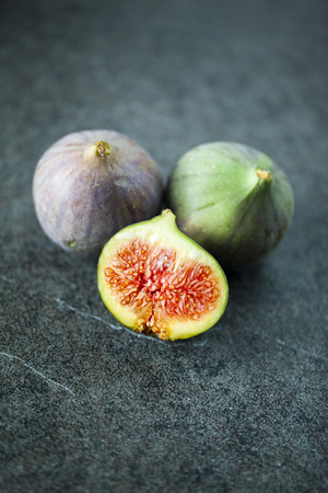 Whole fresh figs and one slice of figs. Focus is on the sliced figの写真素材