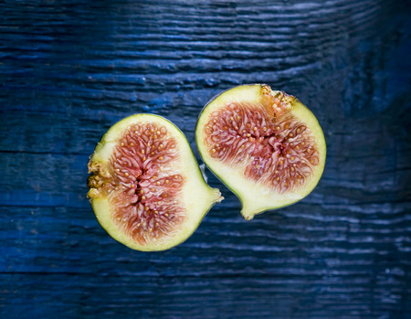 Two slices of fresh figs  on top of wooden table.の写真素材