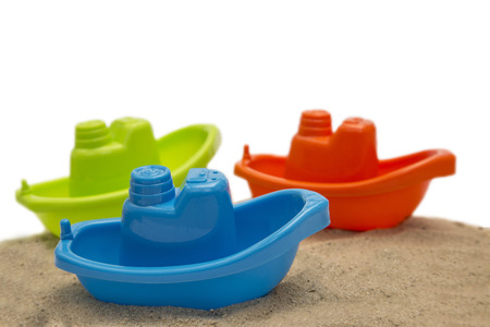 Three plastic toy boat on sand isolated on whiteの写真素材