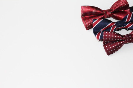 On a white background there are three bow ties for a man. All ties in red and dark colors. This...