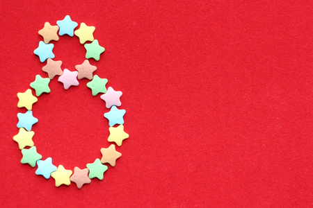 The number eight on a bright red background. Eight lined with small colorful stars. March 8 -...