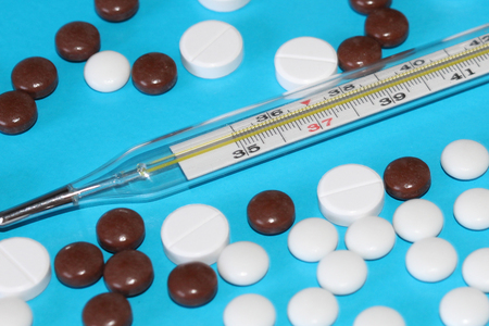 A scattering of medical tablets on the table. Round pills and capsules. Pharmacy. Thermometer for...