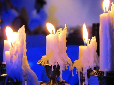 An evening with candles. Many paraffin candles burning on a candlestick. Candles are on the table. Dark.の写真素材