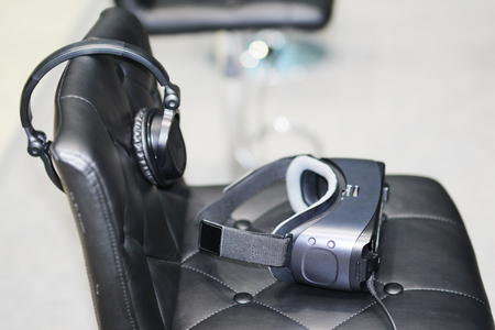 On the chair are glasses for virtual reality with headphones. Goggles-helmet additional reality. Located in the three-dimensional virtual reality.の写真素材