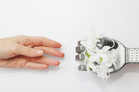 Robot and man. A robot hand gives a real person a flower. Modern technology and robotics. Robots and people nearby. Concept.の写真素材