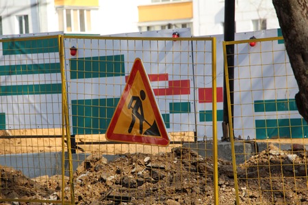 Construction sign - construction work is underway. Construction behind the fence. Road sign. A warning.の写真素材