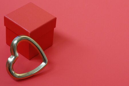 Red gift box with golden hearts. A gift for Valentines Day. The heart is a symbol of love. Gift favorite. Red background. Place for text.の写真素材