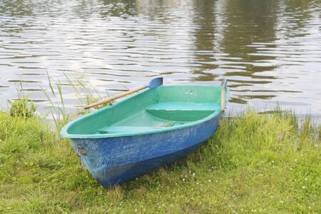 One boat on the lake. Empty fishing boat. Boat for riding tourists. Old wooden boat with a paddle.の写真素材