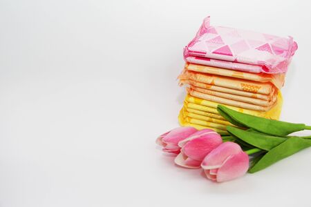 Feminine sanitary pads in the package. Many sanitary pads in individual packaging. Womens pads for monthly use. The photo is decorated with three tulips.の写真素材