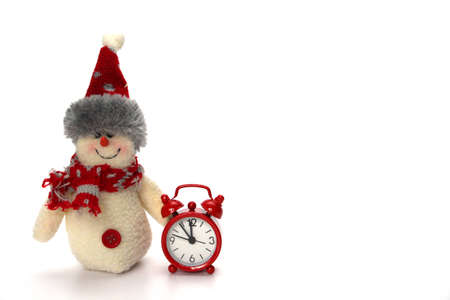 Snowman toy is ready to celebrate Christmas and New Year. Next to the snowman are a red clock, which...