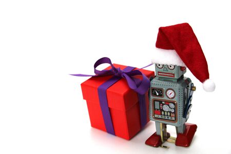 Retro robot with a big gift box. The robot has a Santa hat. Christmas and New Year celebration concept in retro robots style. White background.の写真素材