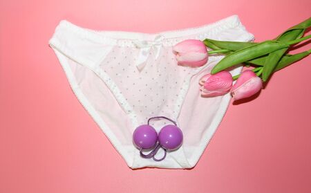 Double pink vaginal balls lie on the panties. The concept of female health. Strengthening the intimate muscles of the vagina. Pink background.の写真素材