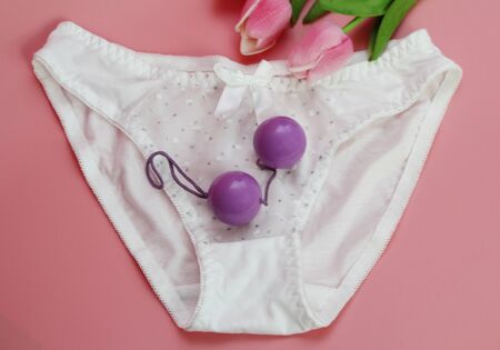 Double pink vaginal balls lie on the panties. The concept of female health. Strengthening the intimate muscles of the vagina. Pink background.の写真素材