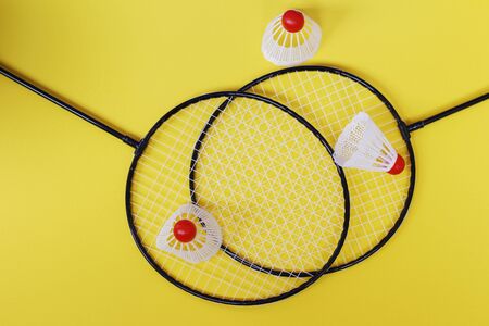Badminton. Three shuttlecocks and two badminton rackets. Colored yellow background. Idea for a magazine. Healthy lifestyle concept.の写真素材