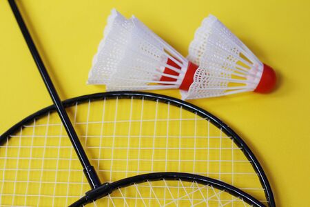 Badminton. Three shuttlecocks and two badminton rackets. Colored yellow background. Idea for a magazine. Healthy lifestyle concept.の写真素材
