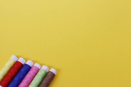 Needlework concept. A lot of multi-colored little bobbins of sewing thread on a yellow background. Plenty of room for text. Skeins of thread for needlework and sewing.の写真素材