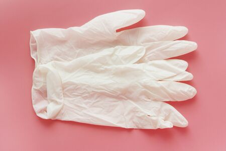 Two white medical gloves on a pink background. Sterile latex gloves. Medical glove for protection...