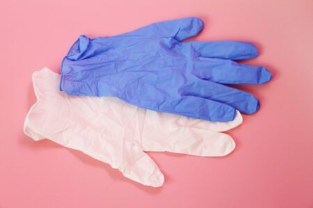 Two medical gloves on a pink background. White and blue latex gloves. Medical glove for protection...