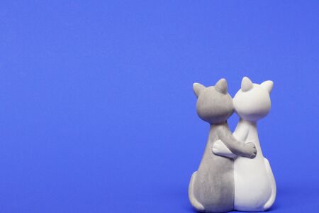 Two cats are hugging. Cats are close and love each other. Valentines Day. Figurine cats in love. Cats together are a symbol of lovers. Congratulation. Place for text. Blue color.の写真素材