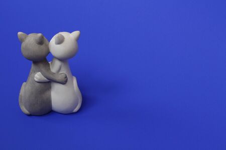 Two cats are hugging. Cats are close and love each other. Valentines Day. Figurine cats in love. Cats together are a symbol of lovers. Congratulation. Place for text. Blue color.の写真素材