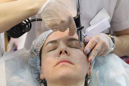 Moscow, RF, 04.19.2019. A cosmologist gives oxygen mesotherapy, oxygen therapy. The girl does anti-aging and medical procedures on her face. In a beauty salon.のeditorial素材