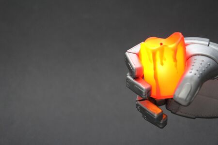 Robot hand with a candle. Mourning, grief, sadness. The sad robot. The candle is off. Robot hand holds a yellow candle. The concept of artificial intelligence. Gray background.の写真素材