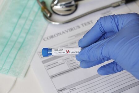Conceptual photography - testing for coronavirus. In the hand is a test tube with a sample of the...