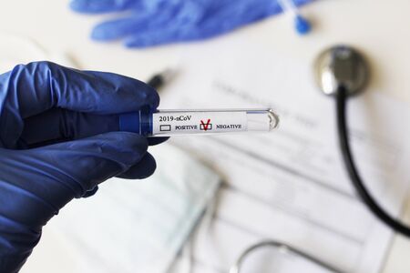 Conceptual photography - testing for coronavirus. In the hand is a test tube with a sample of the...