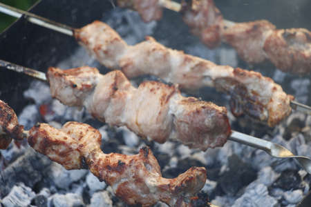 Cooking barbecue skewers. Marinated kebab is grilled on charcoal. Shish kebab barbecue was made of lamb, pork, beef, chicken. Roast beef skewers on barbecue grill. Skewers on skewers.の写真素材
