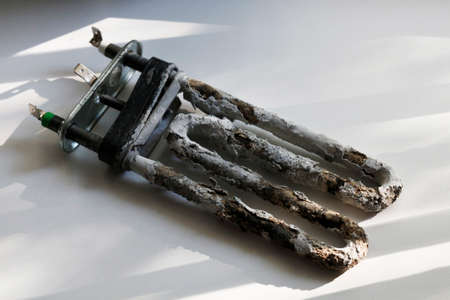 An old limescale heater for a washing machine. Spare parts for a washing machine used in everyday...