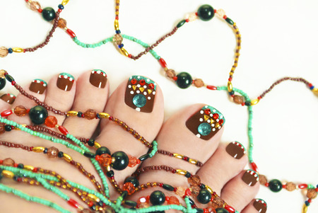Nice pedicure with rhinestones on female legs embellishment from beads on a light background の写真素材