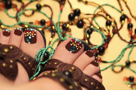 Beautiful brown pedicure with rhinestones and jewelry from beads on a yellow background の写真素材