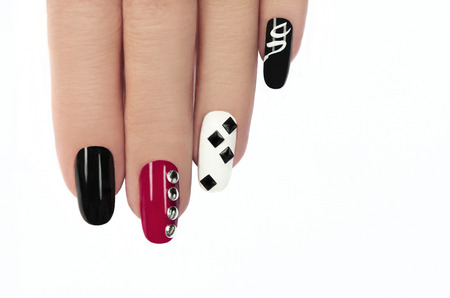 	   Glamorous manicure with different colors of paint and rhinestones square and round shapes on a white background の写真素材